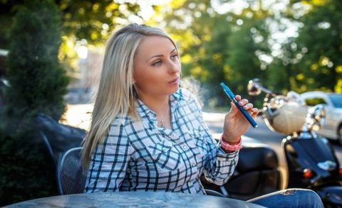 girl with long blond hair tshirt sitting table outside smoking electronic cigarette 613910 15452