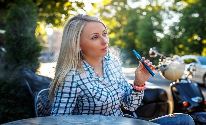 girl with long blond hair tshirt sitting table outside smoking electronic cigarette 613910 15452