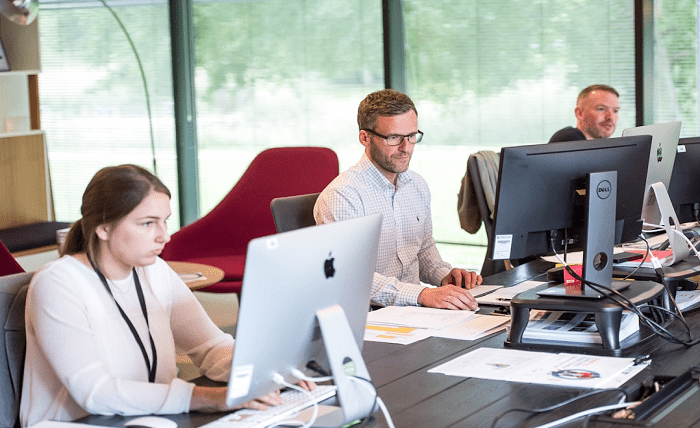Office workers using a computer to research the benefits of switching to online fax services for business communication